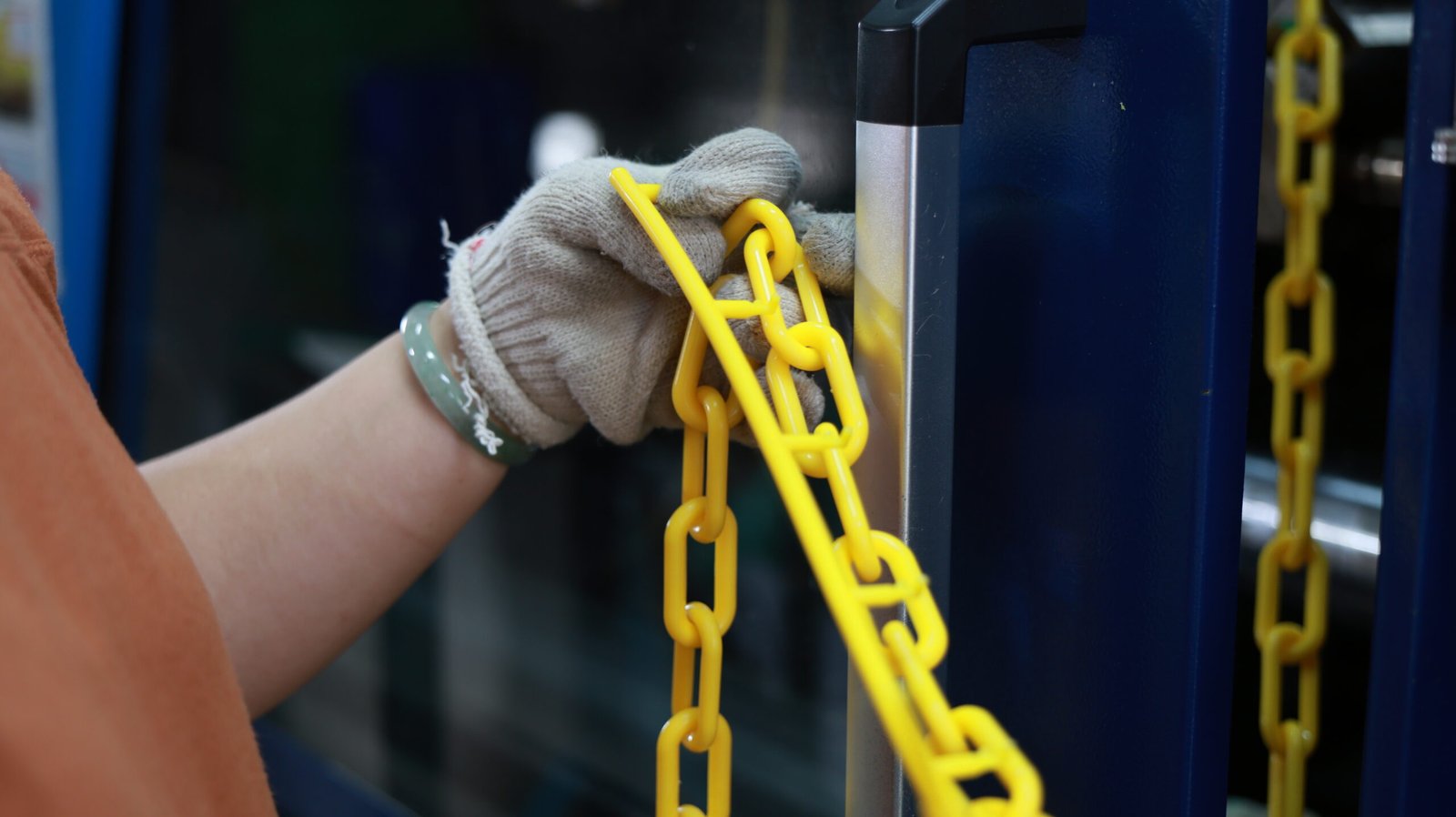 Operator inspecting yellow plastic chain links during production.